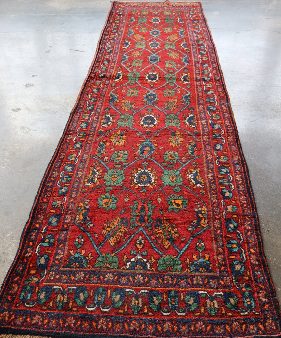 Red patterned runner rug with teal and green medallions and blue edge trim