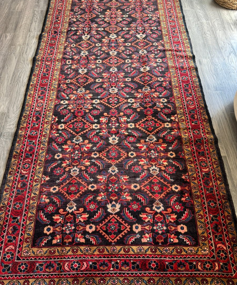 Rectangular Persian-style area rug with dark navy field and red ornamental border