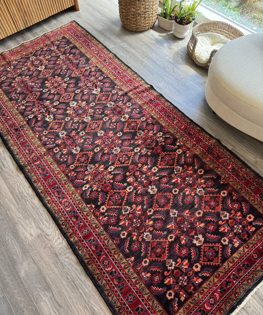 Persian-style runner rug with dark navy field and red geometric border