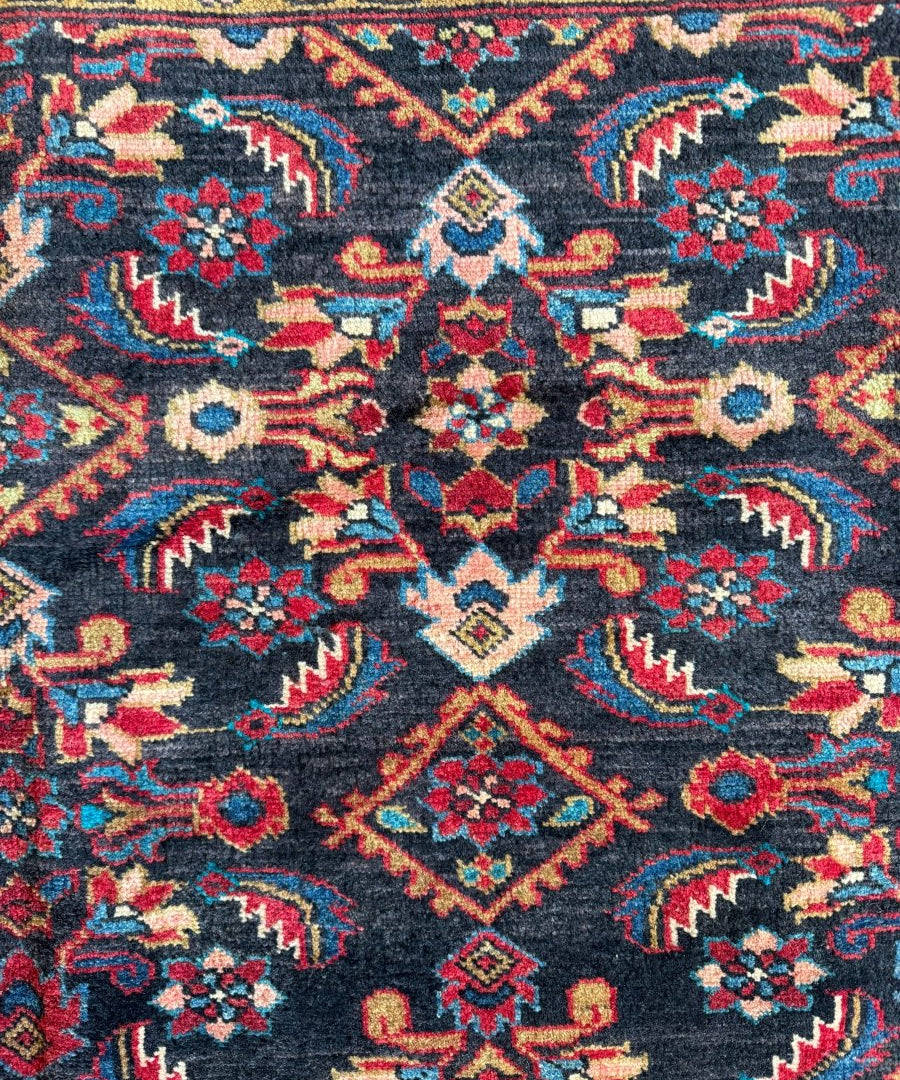 Close-up Persian-style rug pattern with navy background and red blue medallions