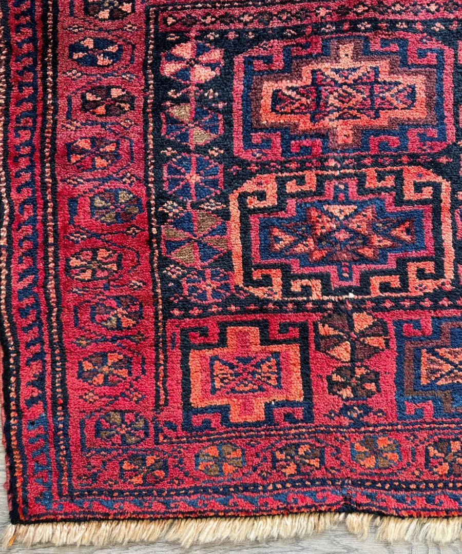 Persian Lori rug with red border and navy geometric medallion patterns