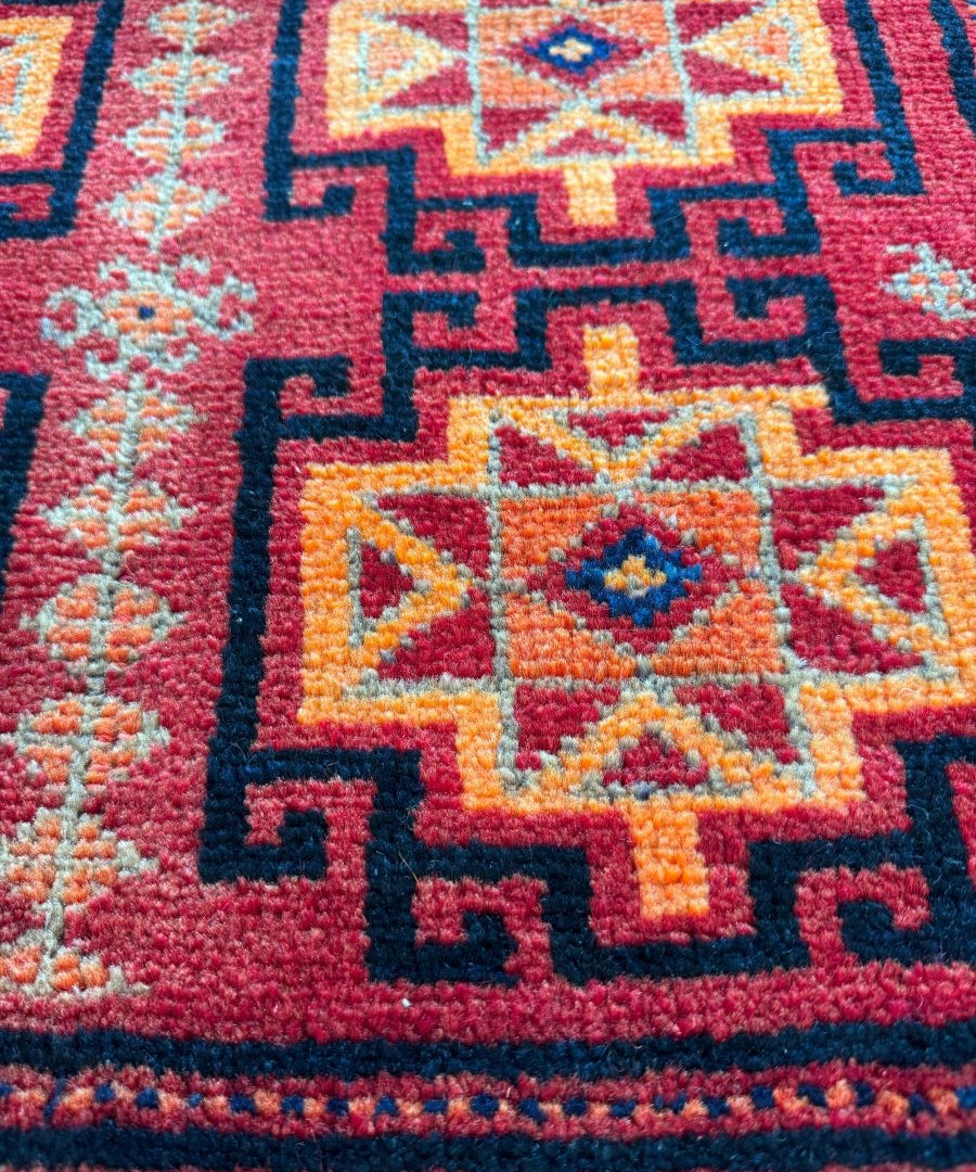 Persian Lori rug close-up, maroon and cream star motifs with blue patterned border