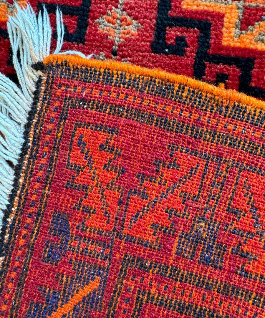Persian Lori rug corner detail, light blue fringe and red geometric grid pattern
