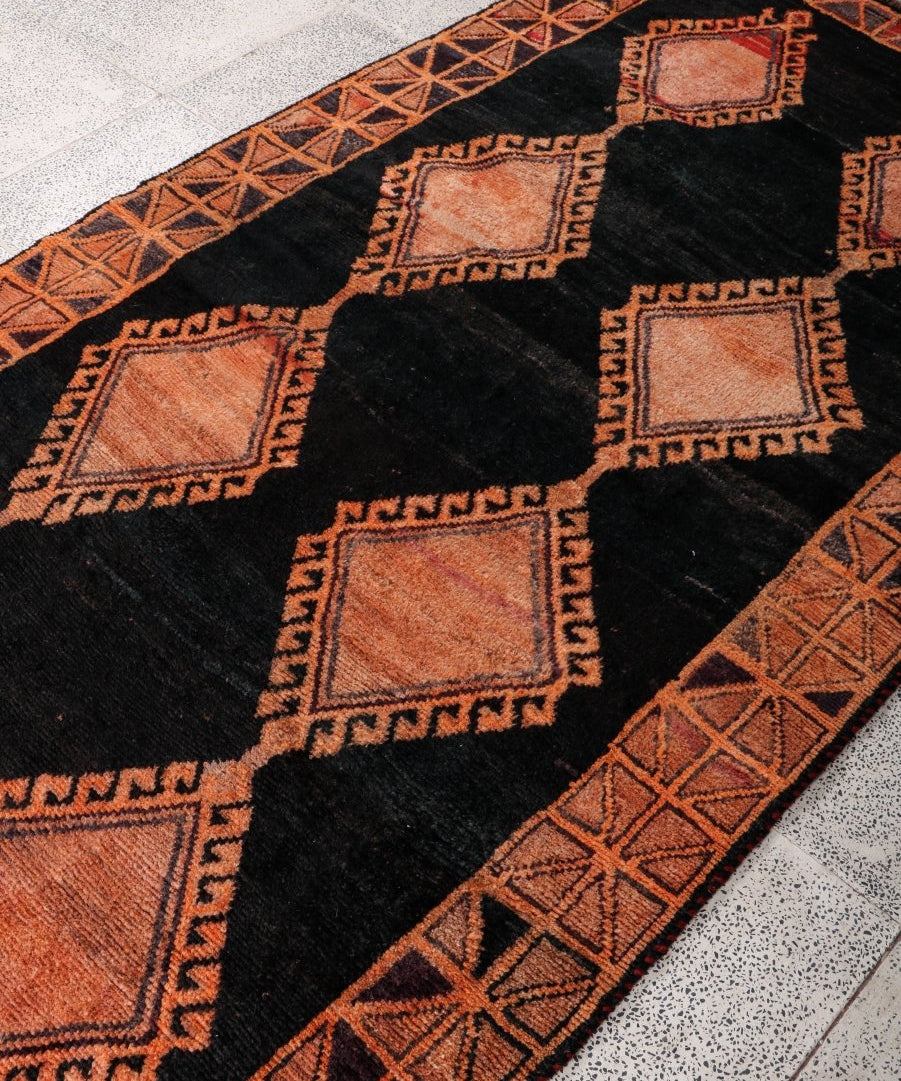 Persian Lori rug corner detail, black background with rust and beige motifs