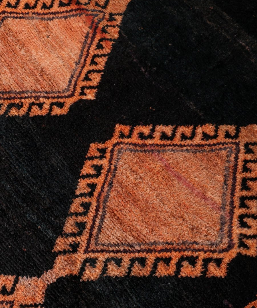 Persian Lori rug close-up of black field with rust and beige square motif