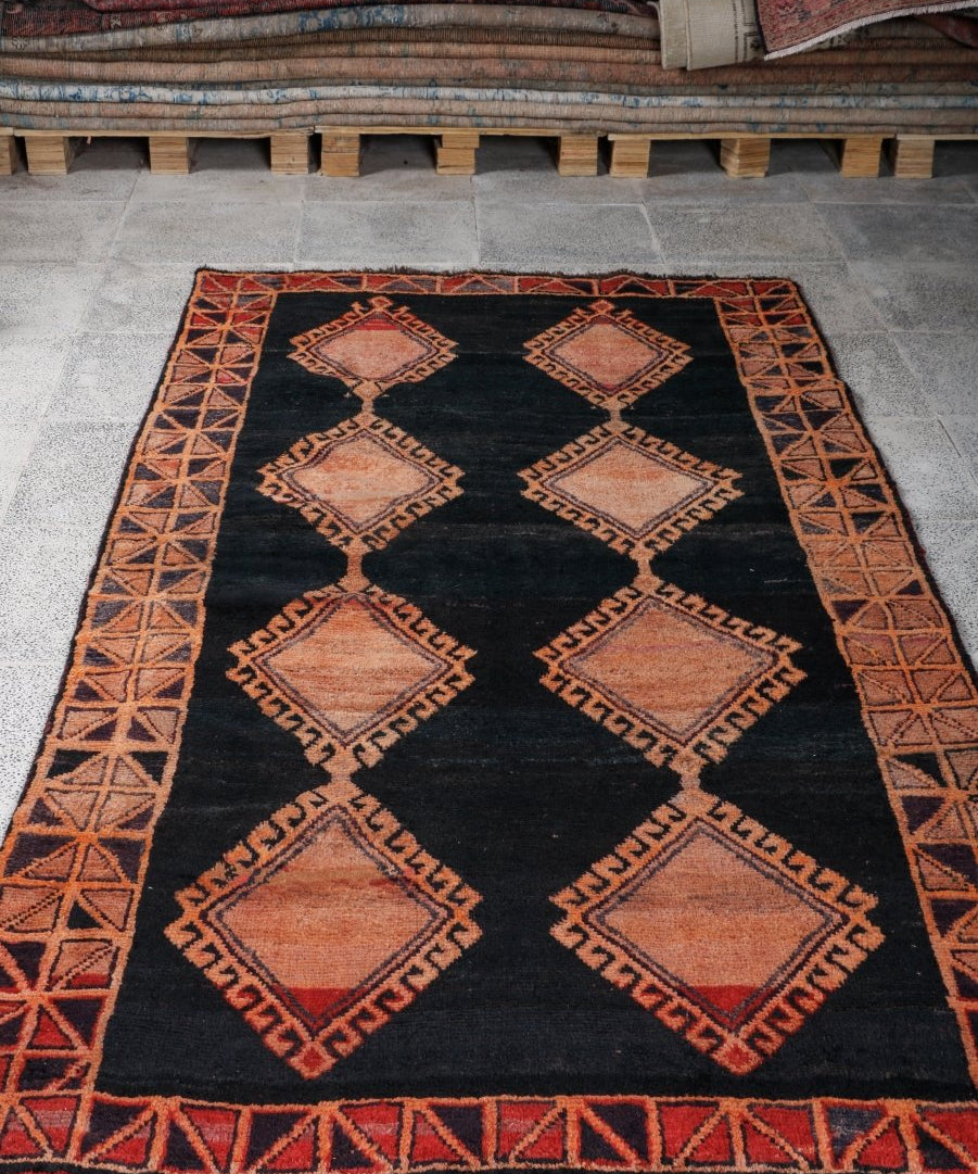 Persian Lori rug, black field with rust border and repeating diamond pattern