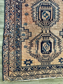 Persian Luri-style rug with beige base and dark navy geometric medallions