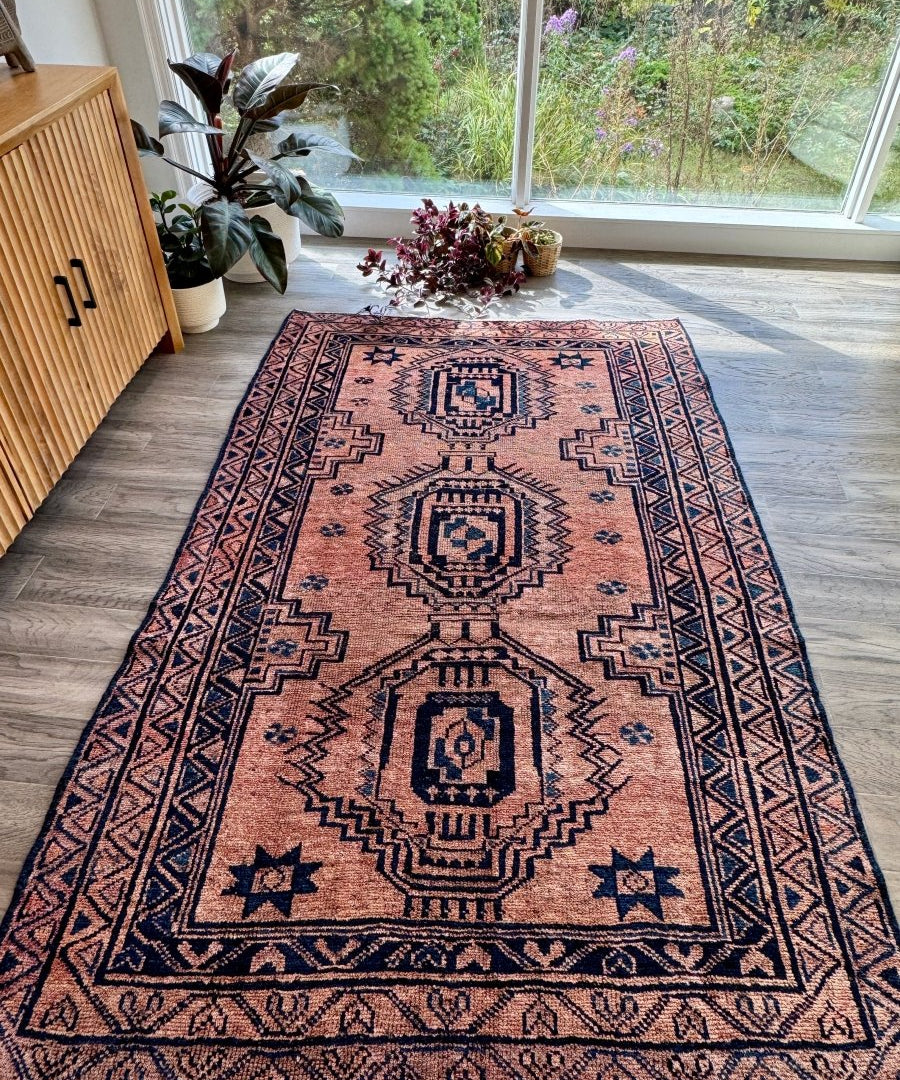 Persian Luri-style rug with dusty rose field, navy diamond motifs, and border
