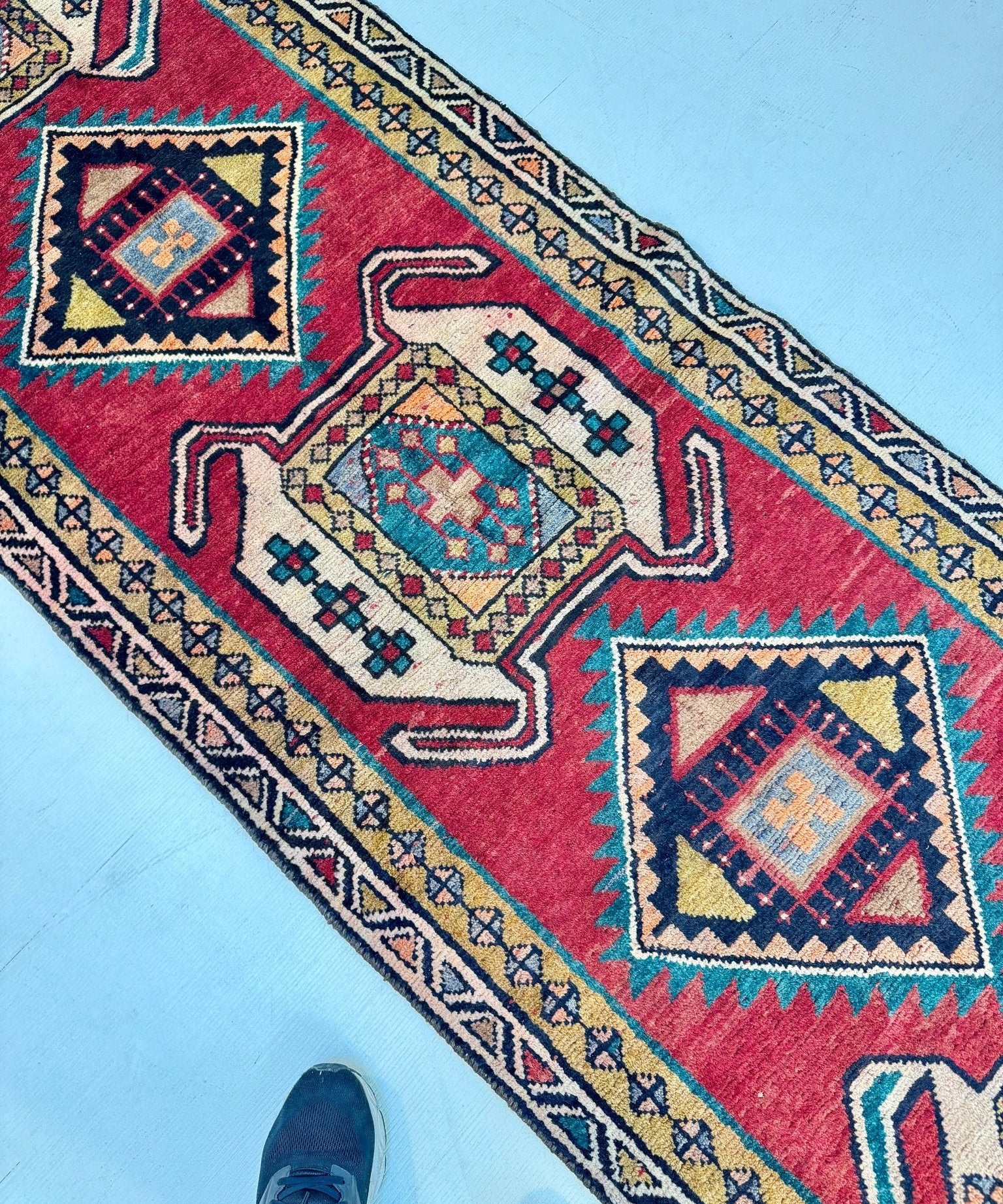 Persian Luri runner rug angled view of red panels with cream and teal geometric motifs