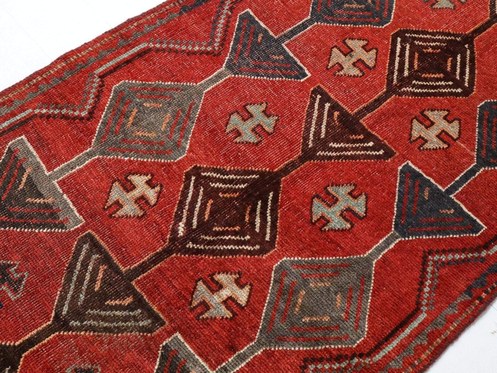 Close-up of red rug surface with outlined hexagon motifs and dark patterned accents.