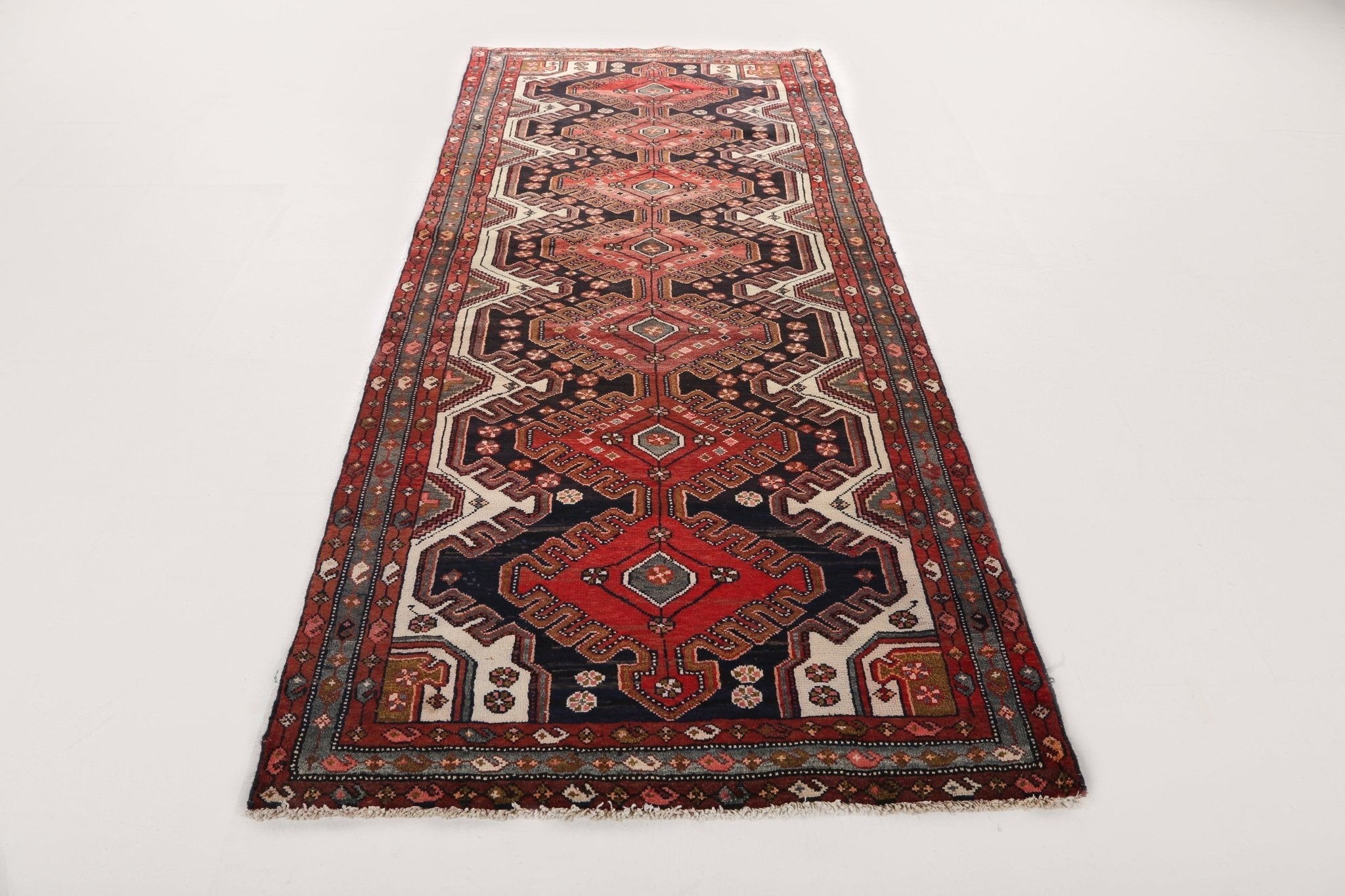 Persian runner rug with central medallion and repeating geometric motifs in red, black, and cream.