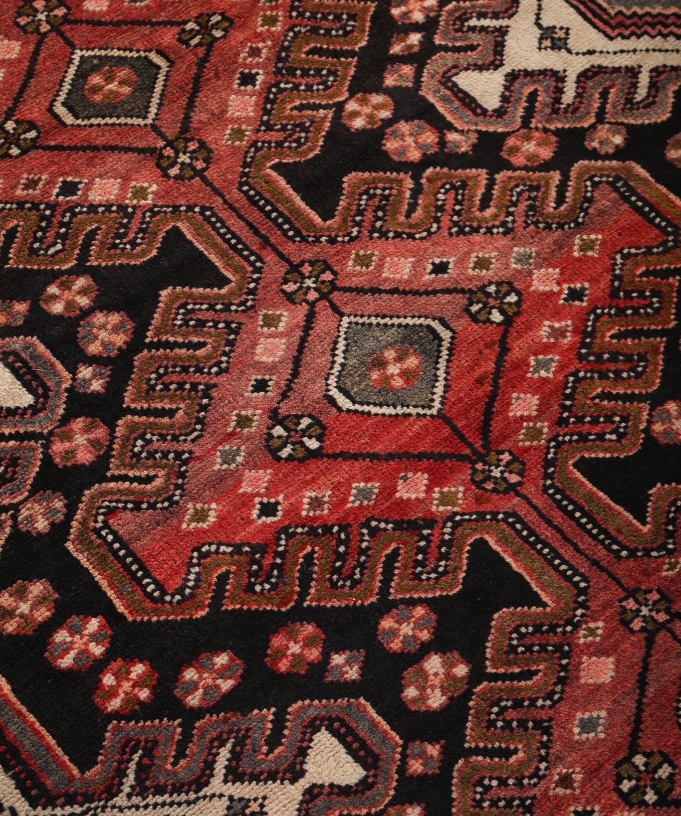 Runner rug pattern close-up with starburst motifs in red, brown, and dark navy with cream.