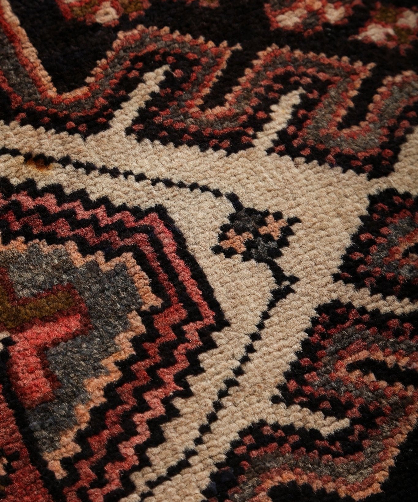 Close-up of runner rug texture with bold geometric motifs in cream, black, and rust red.