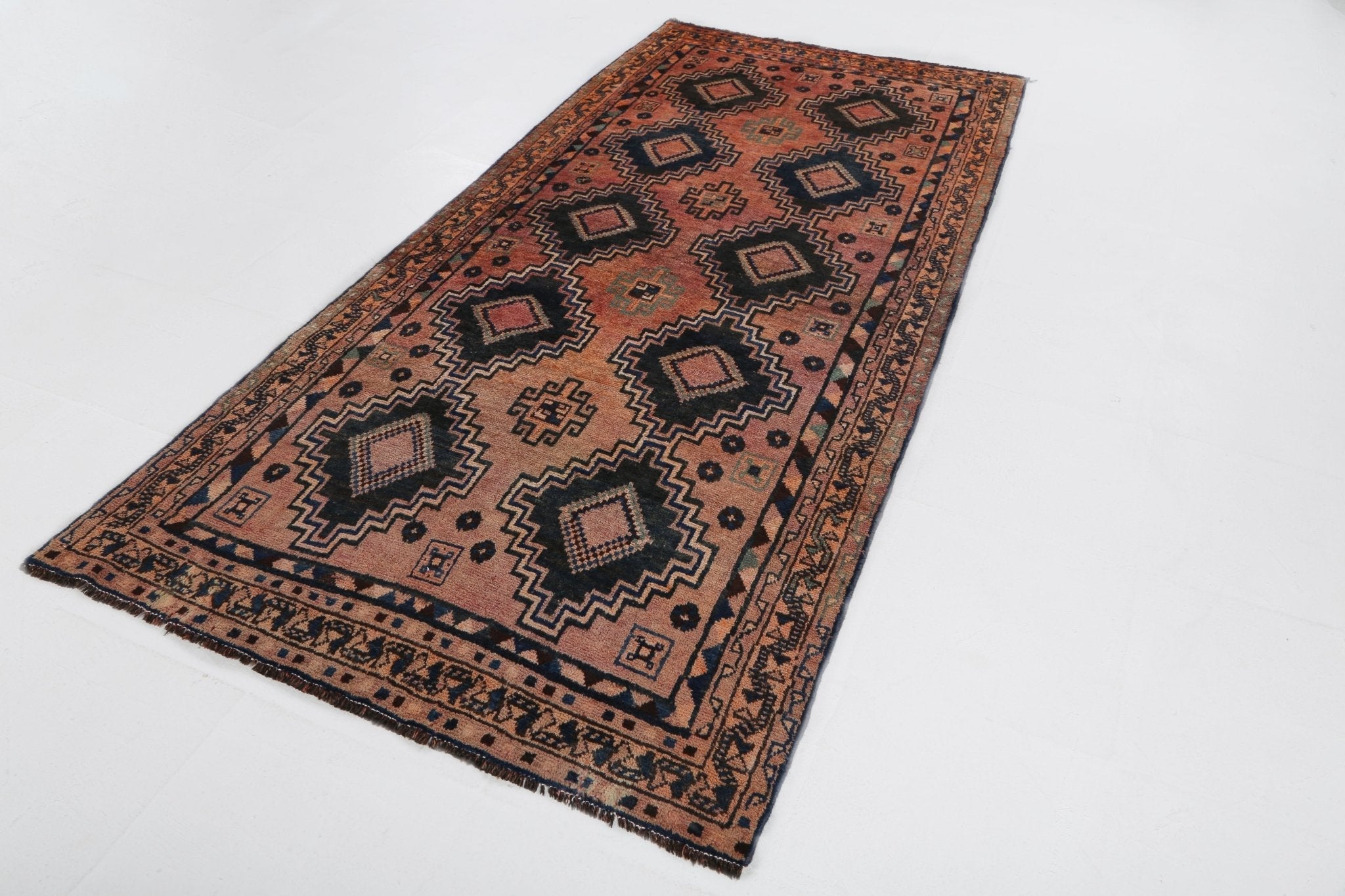 Runner rug with rust, tan, and navy diamond and border motifs on a flat weave.