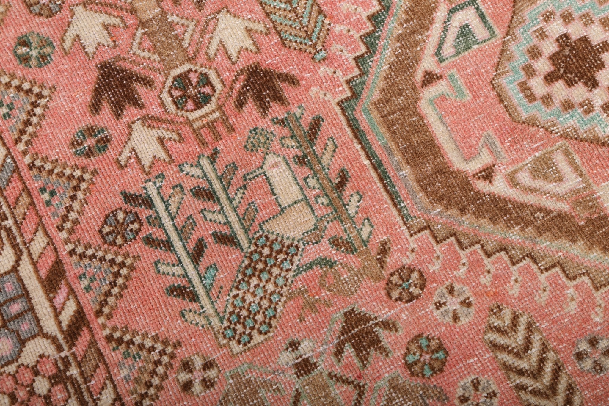 Rug with coral and tan floral and geometric motifs with dark blue accents