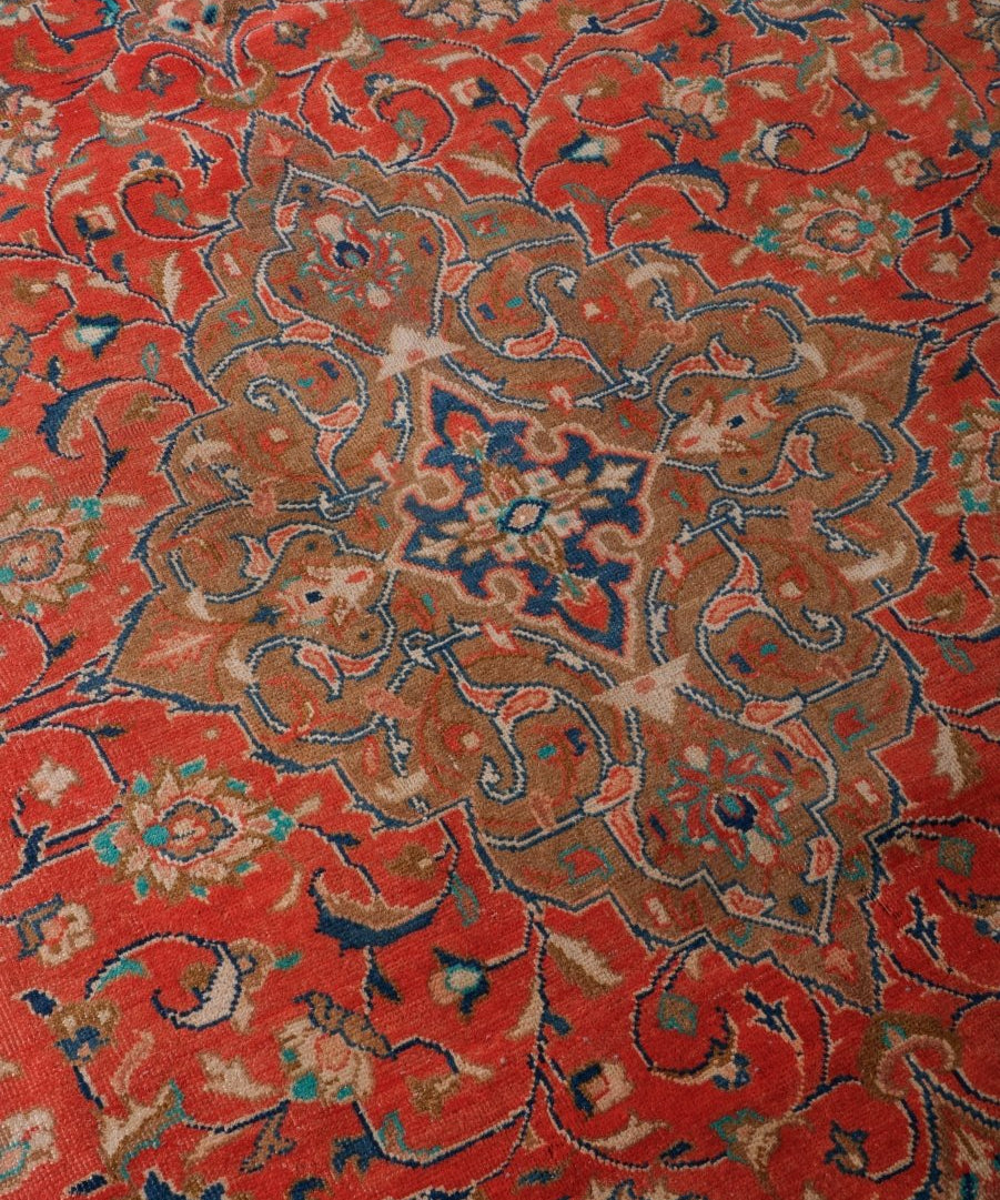 Close-up of red Persian-style rug pile with blue and beige floral scrollwork