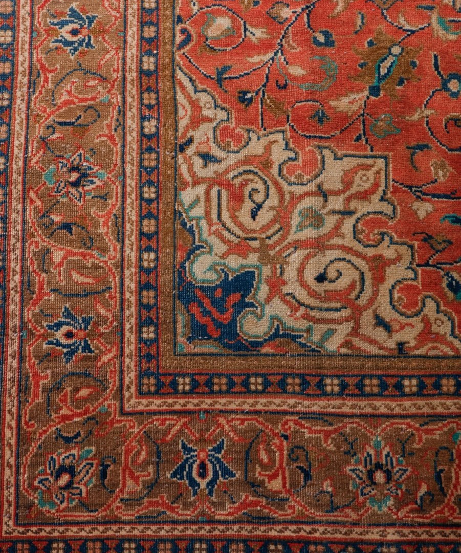 Persian-style rug corner detail with red field, navy frame, and beige motifs