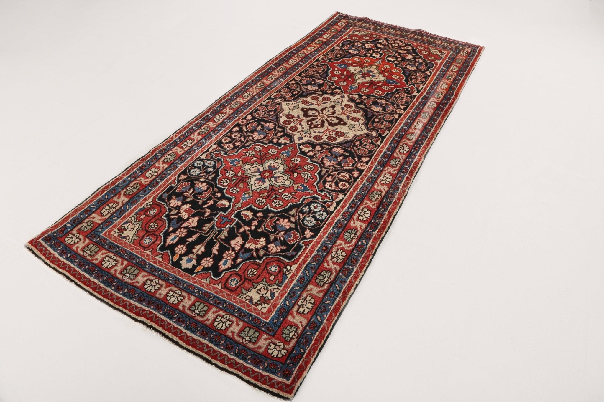 Persian-style runner rug laid flat with central medallion pattern in red, navy, and cream.