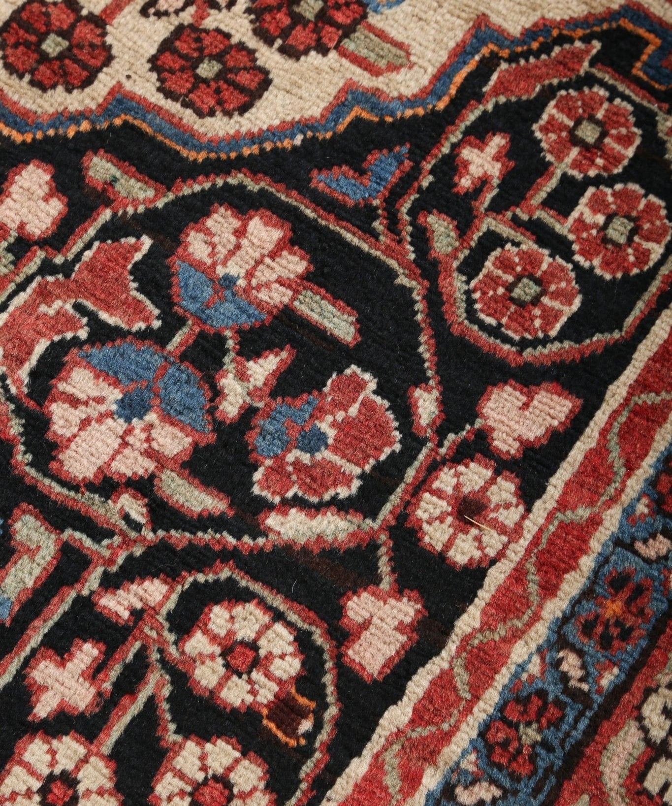 Persian-style runner rug textured weave close-up with small medallion motifs in red and navy.