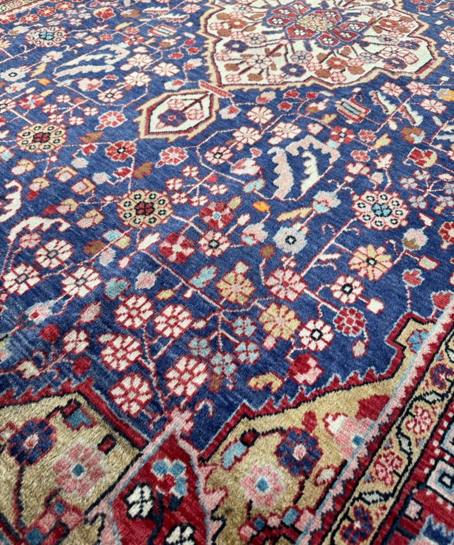 Persian Malayer rug close-up with navy blue pattern, red and cream motifs, and scalloped lines