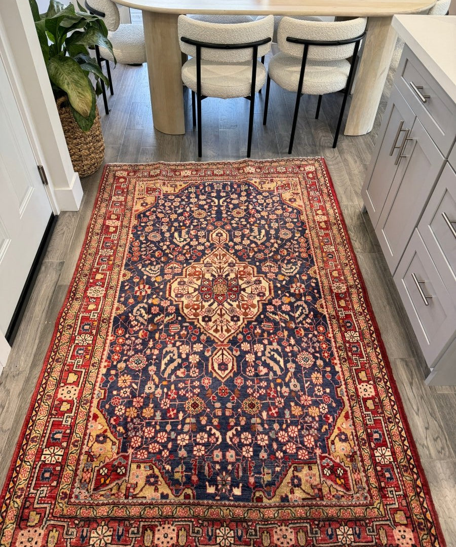 Persian Malayer area rug with navy blue center medallion, cream accents, and red border