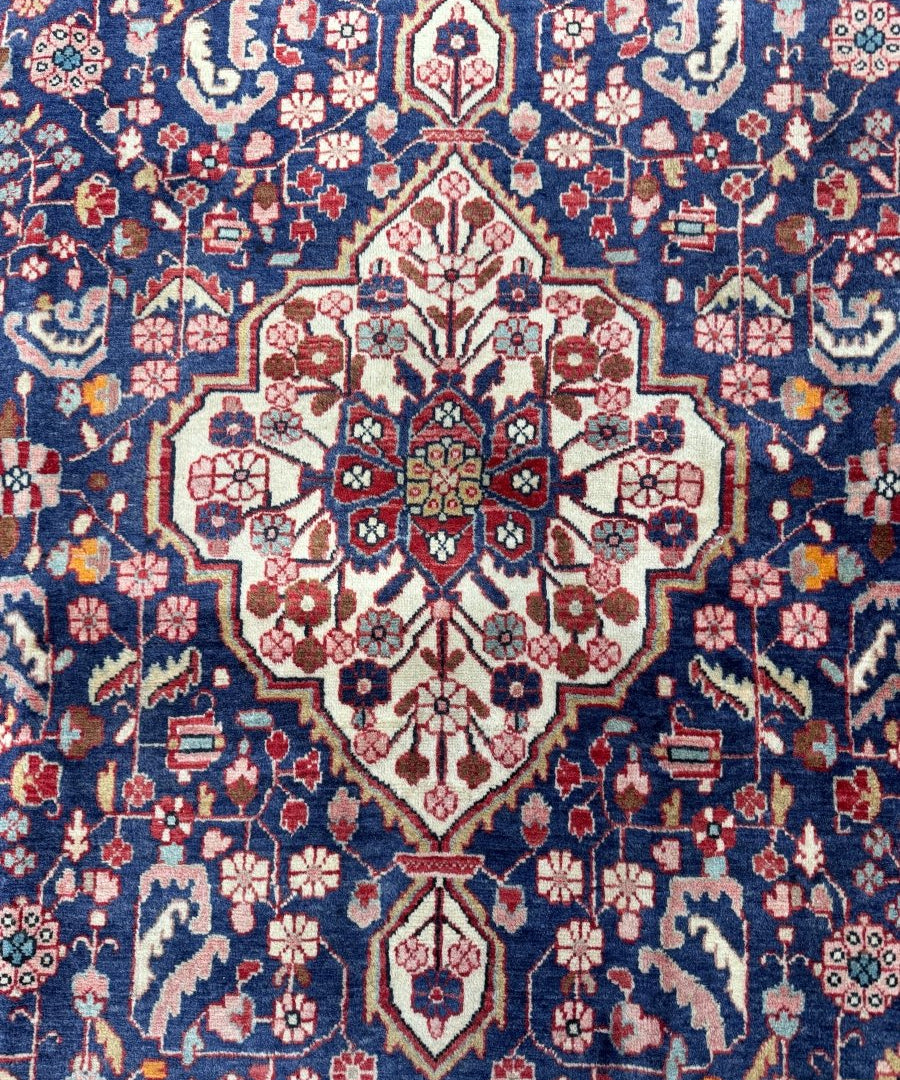 Persian Malayer rug close-up: navy blue background with central cream medallion and red details
