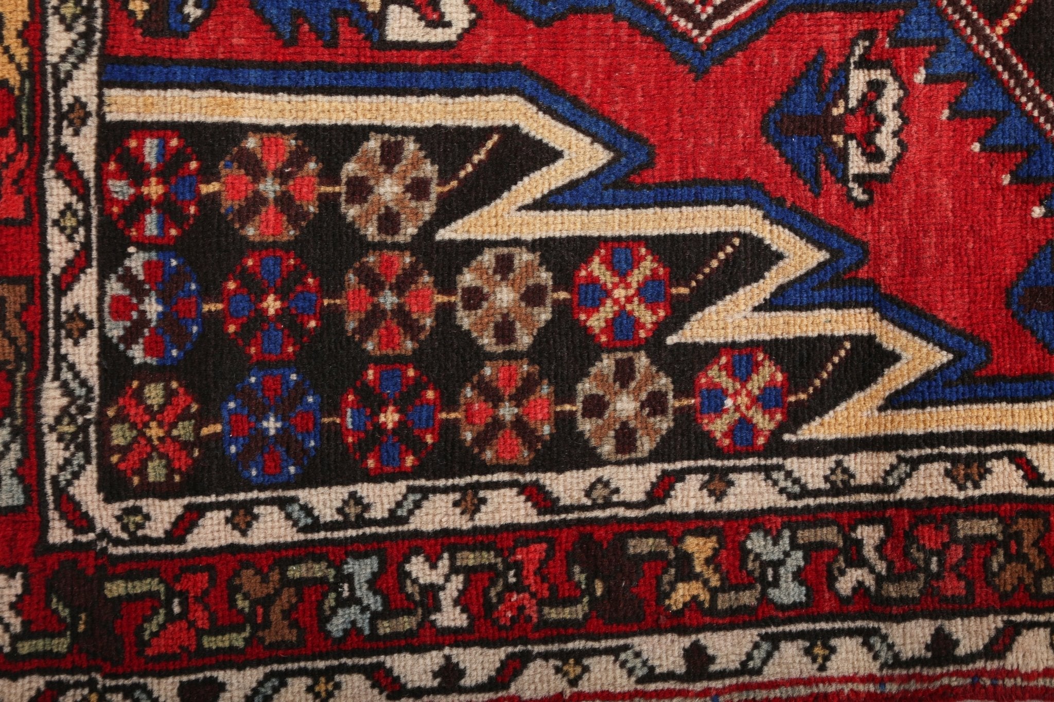 Persian Mazlaghan rug close-up of red field with geometric diamond motifs