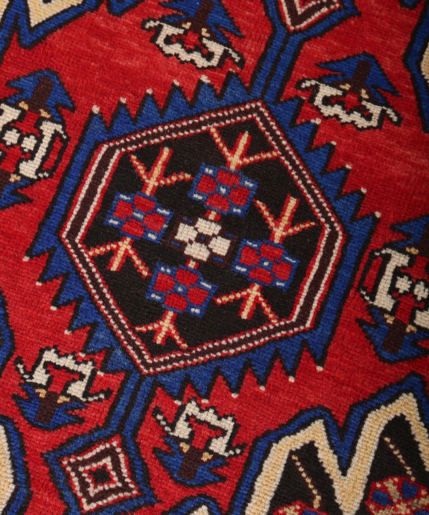 Persian Mazlaghan rug close-up of central medallion with red, blue, cream, and black motifs.
