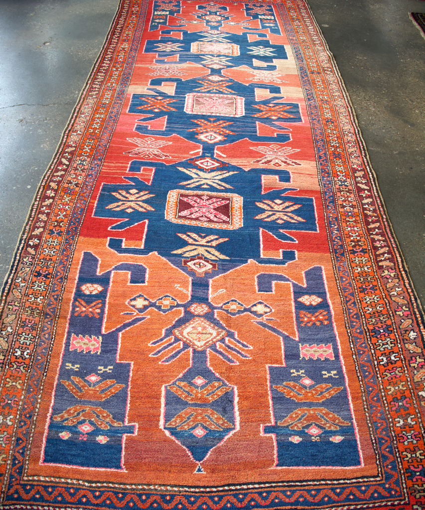 Full runner rug with rust field, blue central medallion, and patterned border.