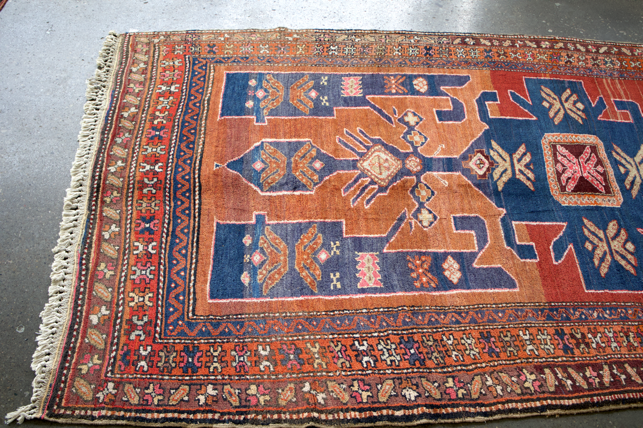 Persian Arshaq meshkin rug angled view with blue center and rust-toned border