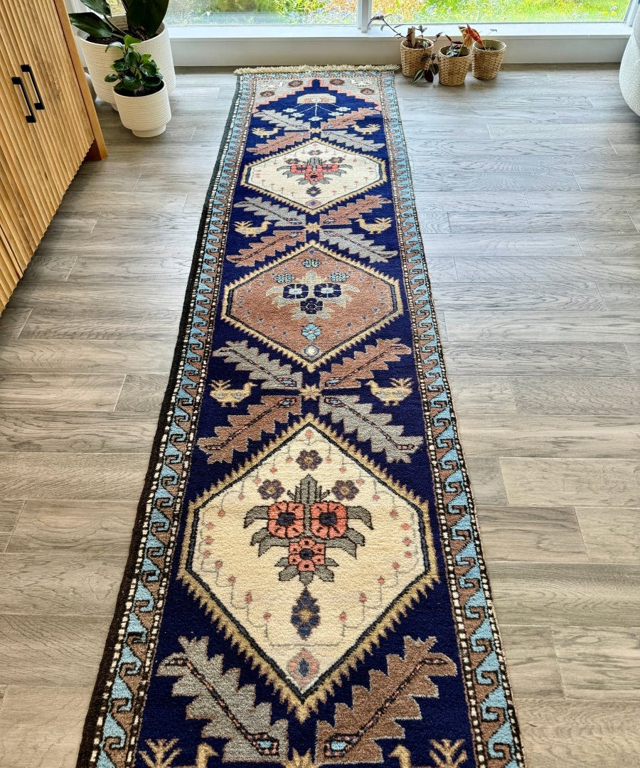 Persian Meshkin runner rug laid flat, navy with cream diamond medallions and zigzag border