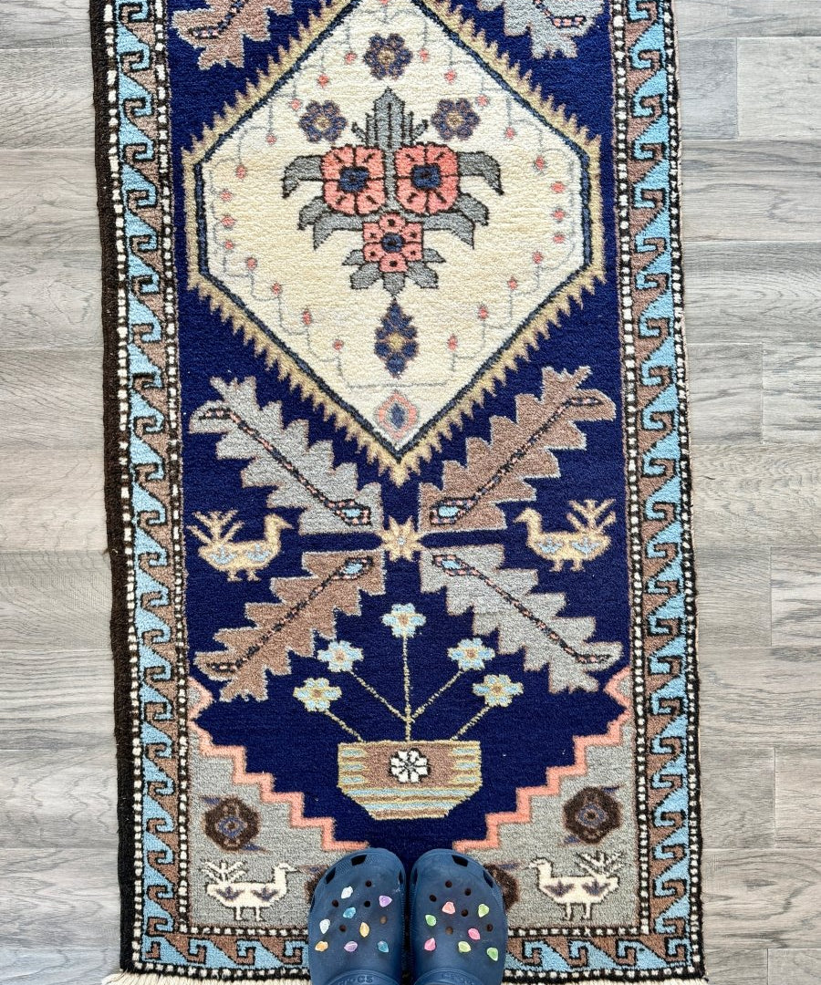 Persian Meshkin runner rug with cream field, navy border, and pink flower medallion