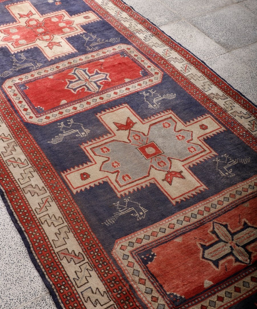 Close-up of runner rug corner; navy ground with red and cream star and border details.