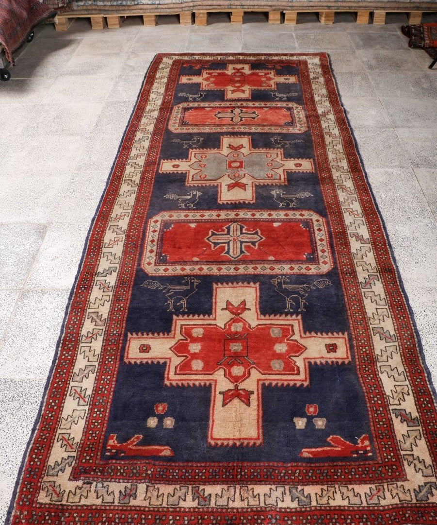 Runner rug flat on floor with navy background, red accents, and central cross medallion.