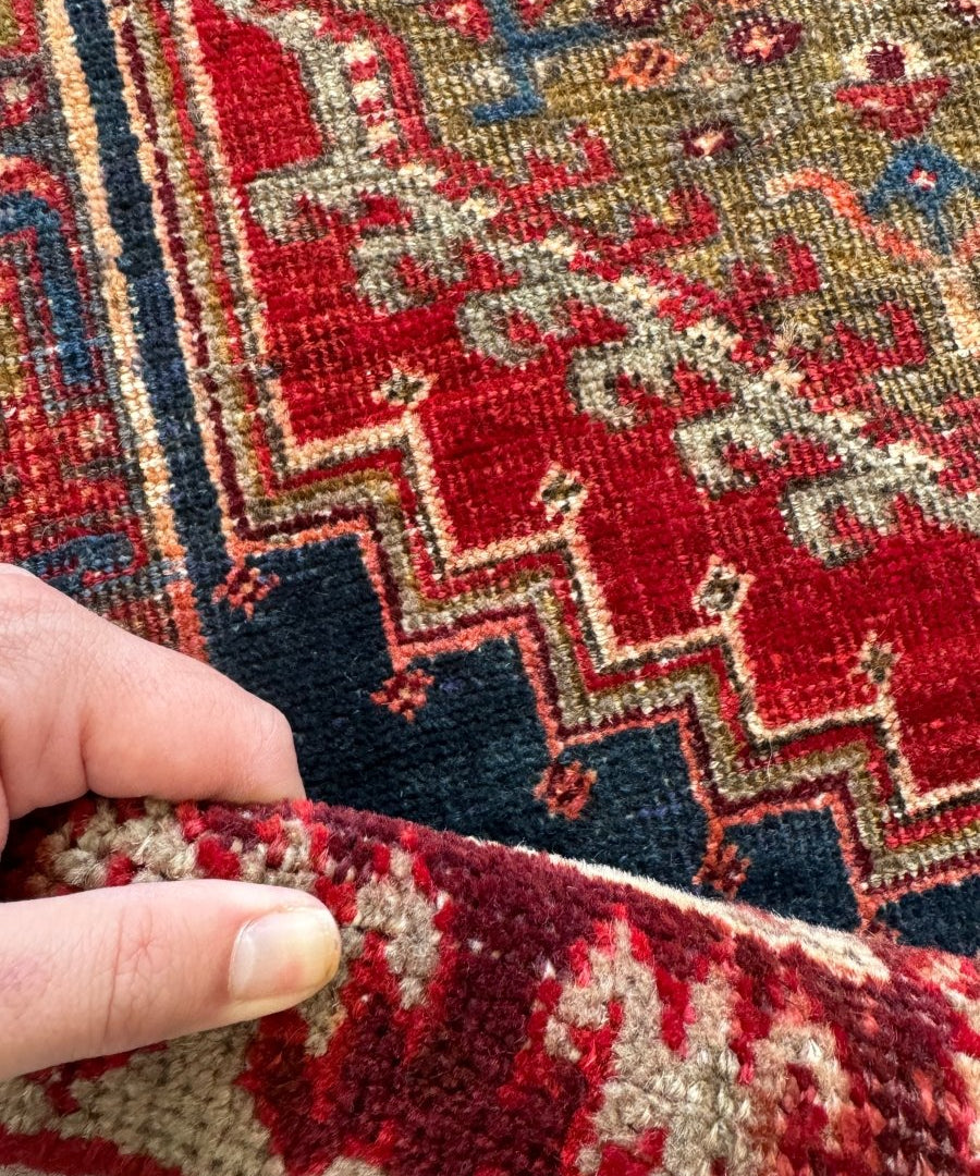 Persian Meshkin runner rug edge with visible weave and red, cream, and blue pattern.