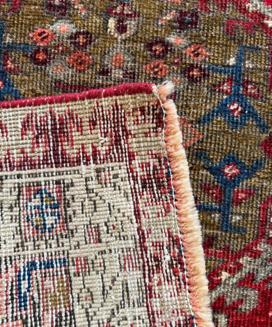 Persian Meshkin runner rug corner showing cream backing and knotted fringe edge.