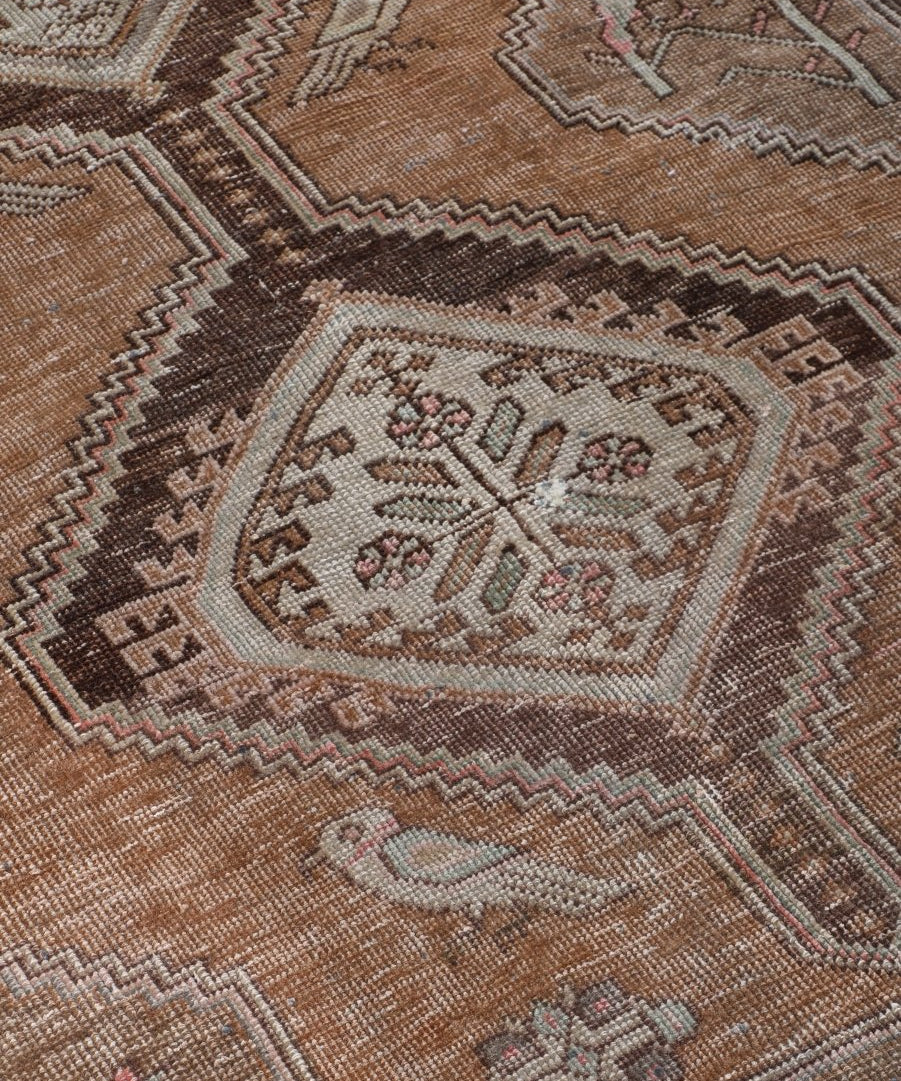 Close-up tan runner rug with multicolor geometric motifs and dark patterned border.