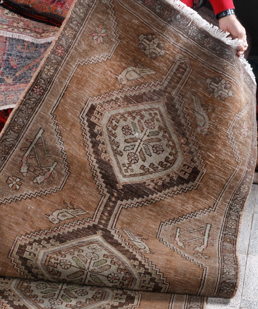 Runner rug with tan field, detailed medallions, and zigzag motifs; fringed edge.