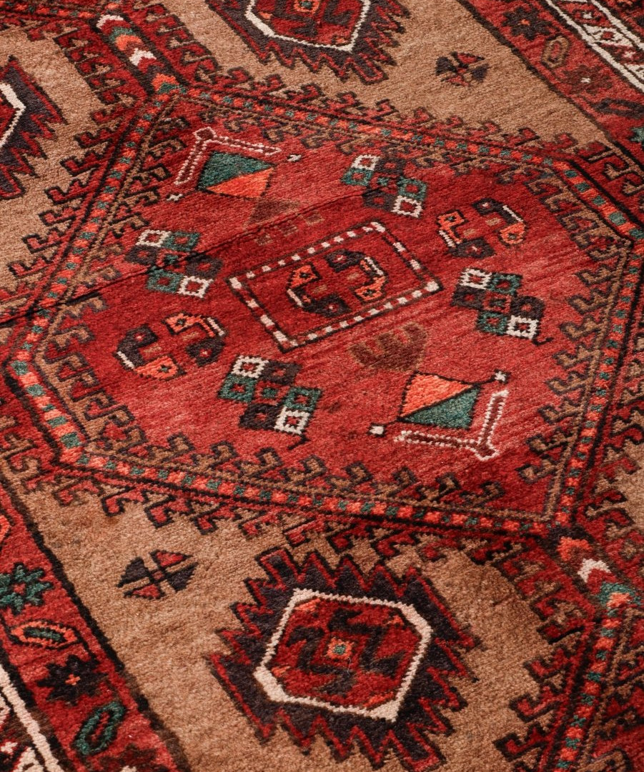 Close-up Persian runner rug weave with red, beige, and navy geometric motifs