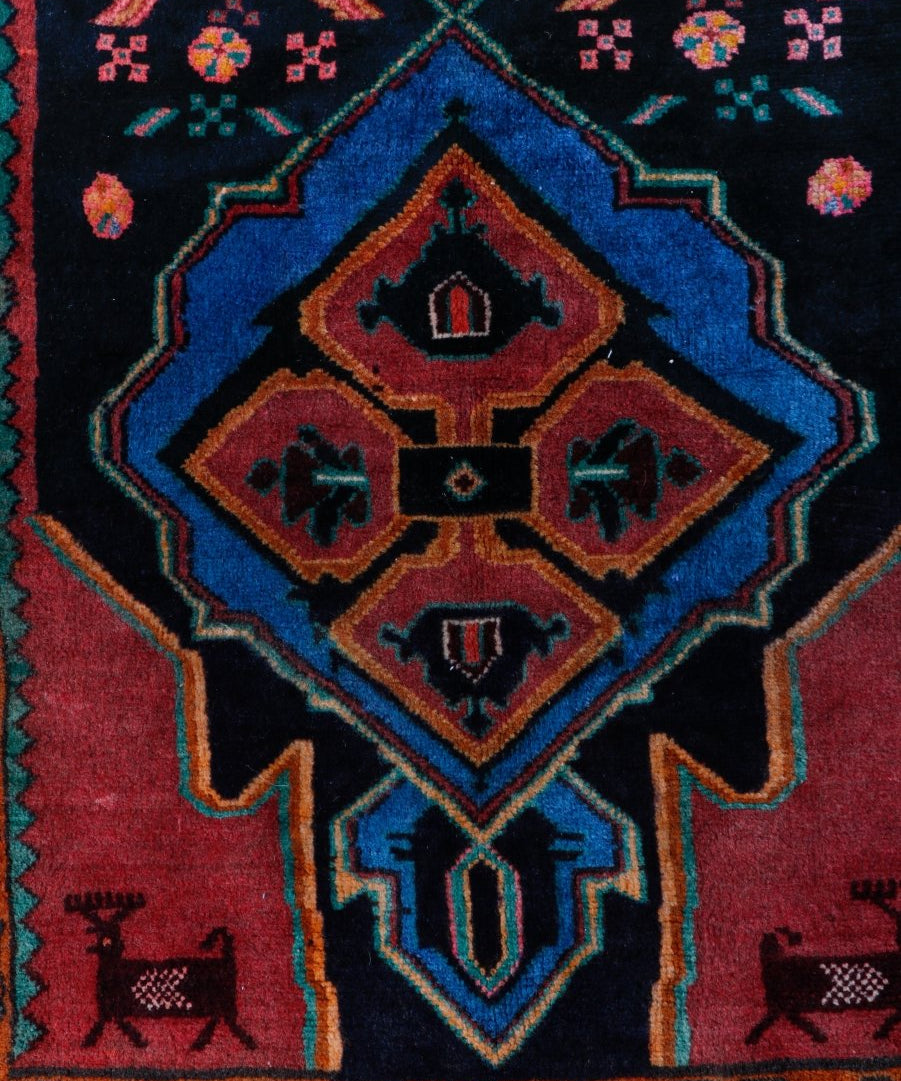Persian meshkin rug close-up: central diamond medallion in blue, red, and gold with small motifs.