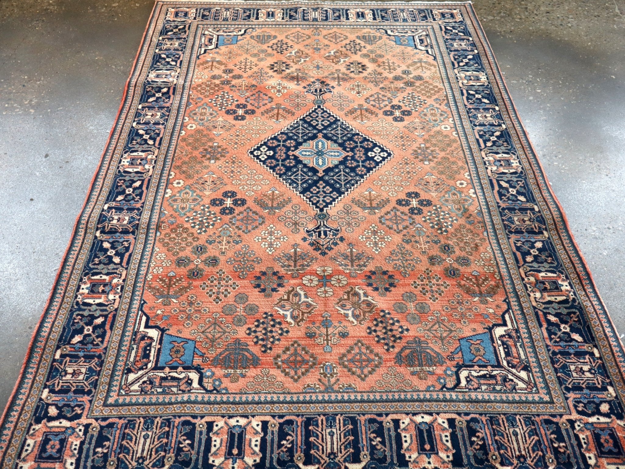 Rust and navy Persian-style rug with diamond medallion, blue corner tiles, fringed edge