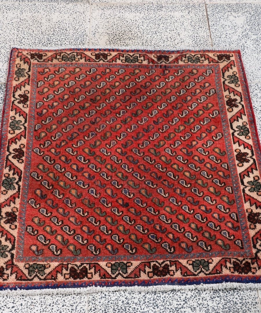 Red Persian-style area rug with repeating motifs and decorative border, square shape.