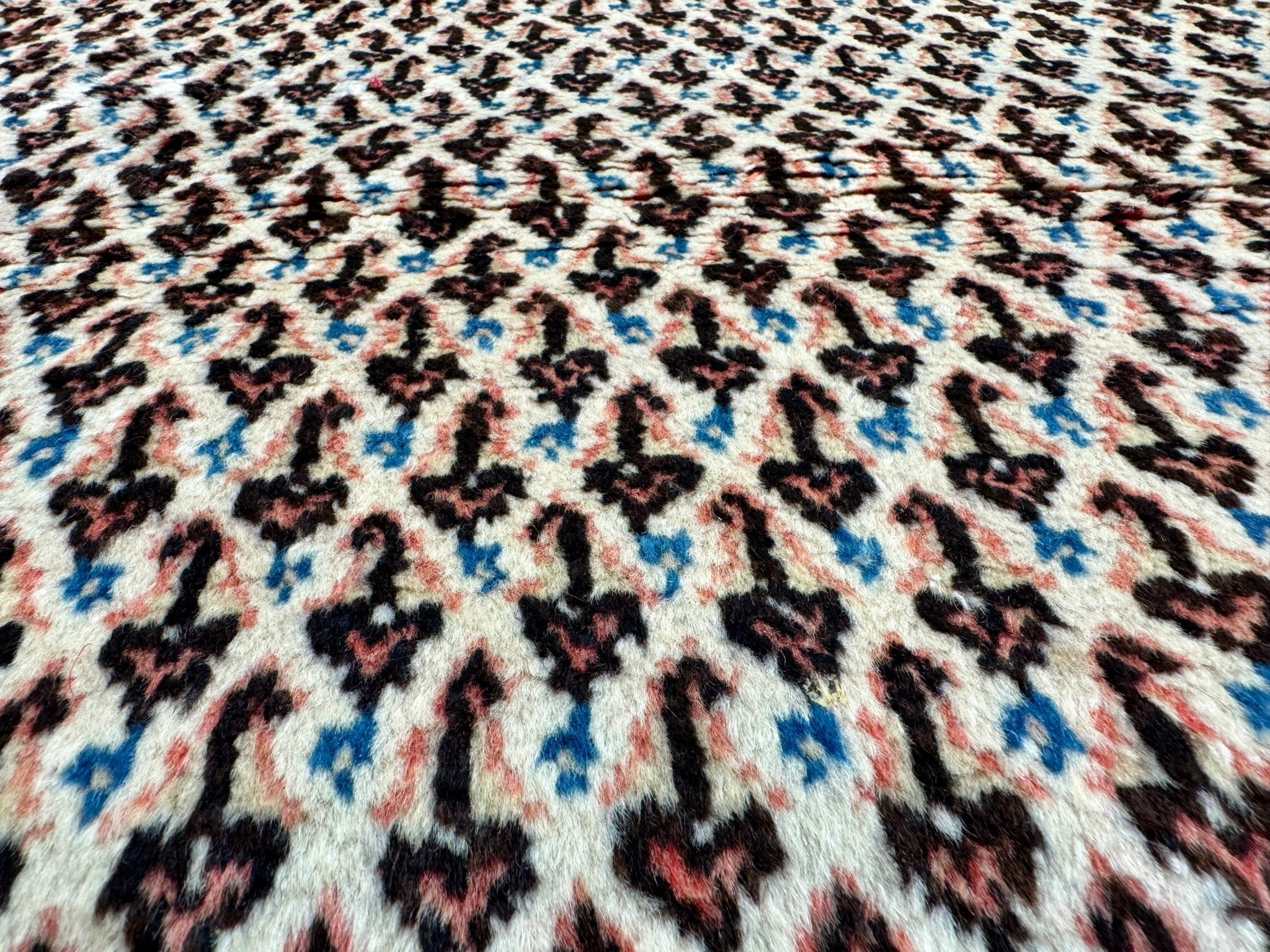 Persian Mir-Boteh rug top view pattern with cream field and scattered light-blue accents.