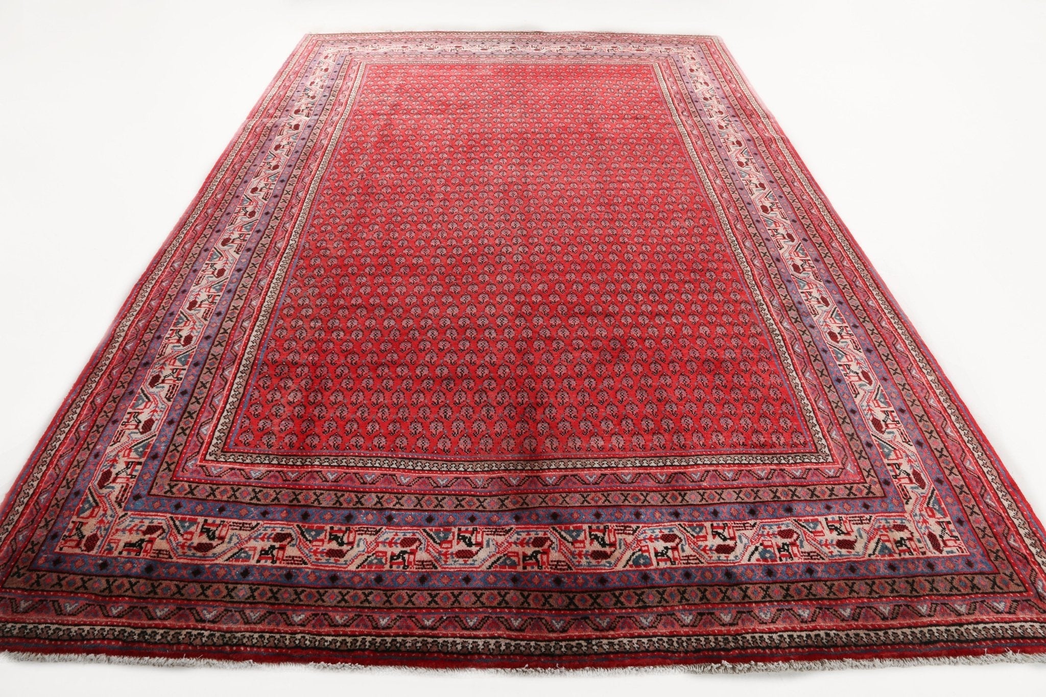 Red Persian-style rug with dark blue and beige border; wide patterned stripe band