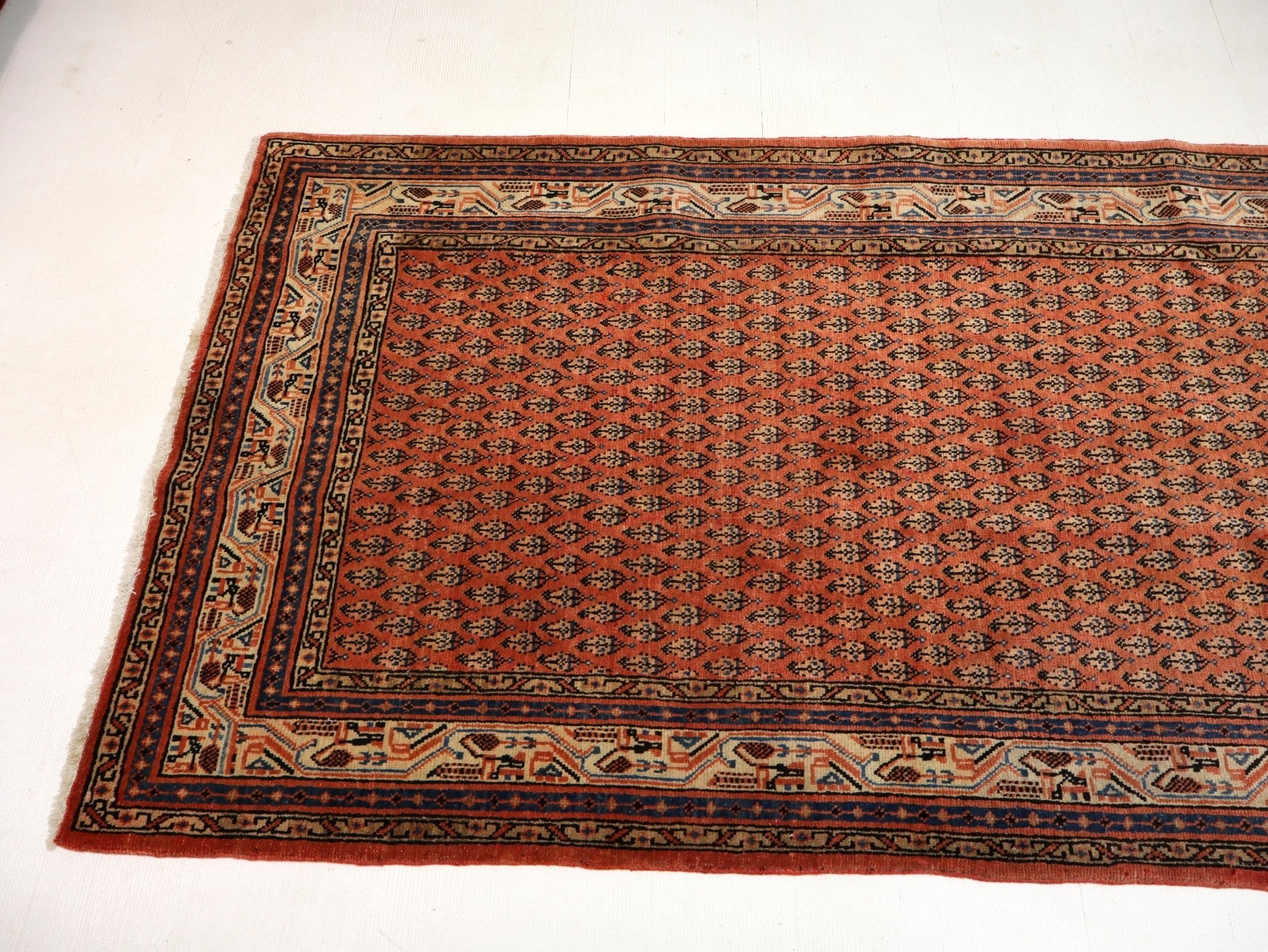 Red Persian-style area rug with geometric motif pattern and detailed border, rectangular.