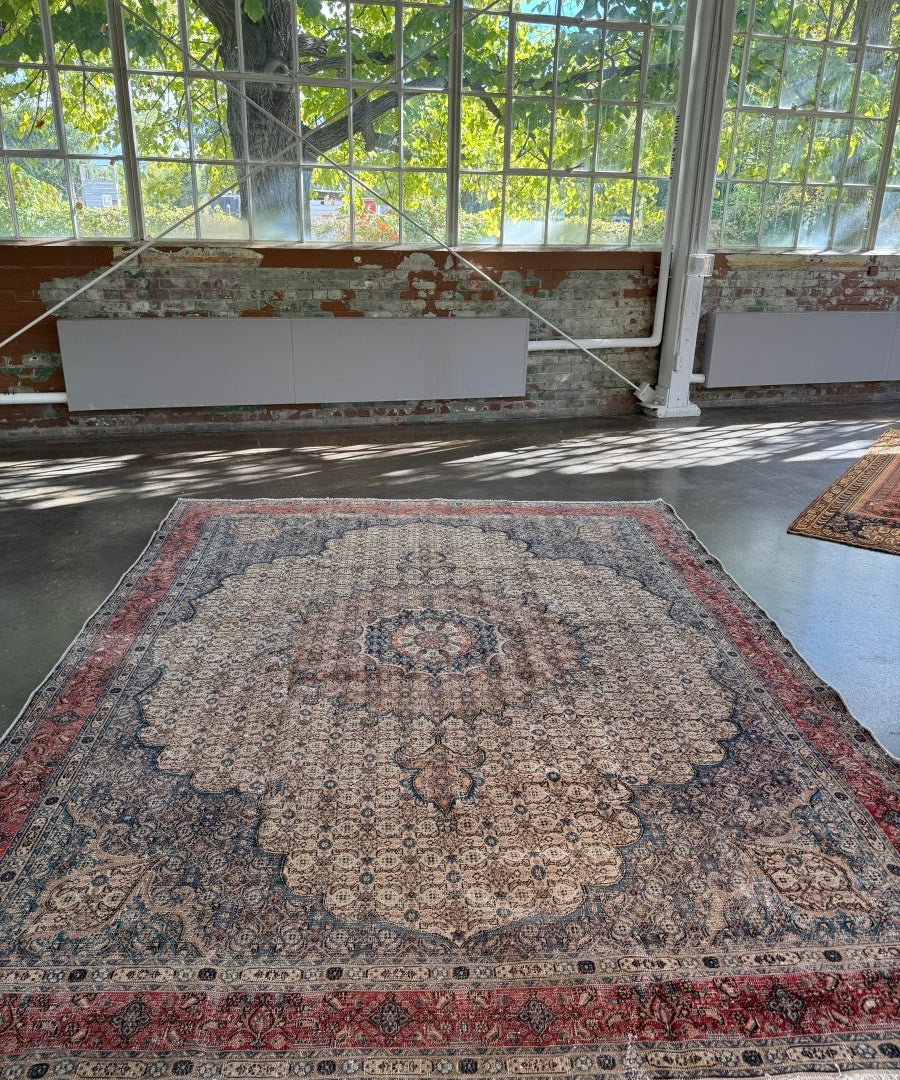 Persian-style rug centered on floor with beige medallion and red border