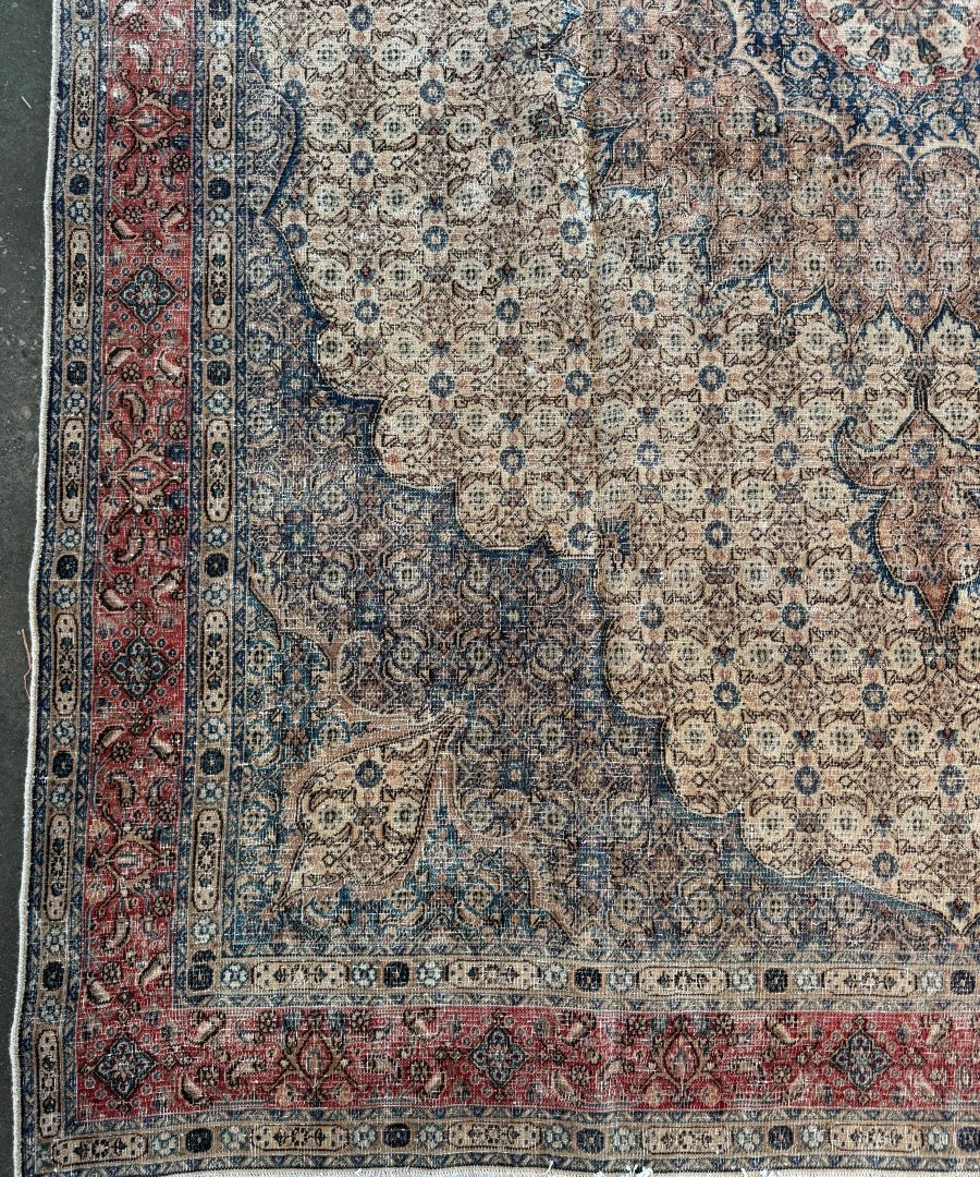 Persian-style rug with blue, beige, and red geometric border and medallion motifs