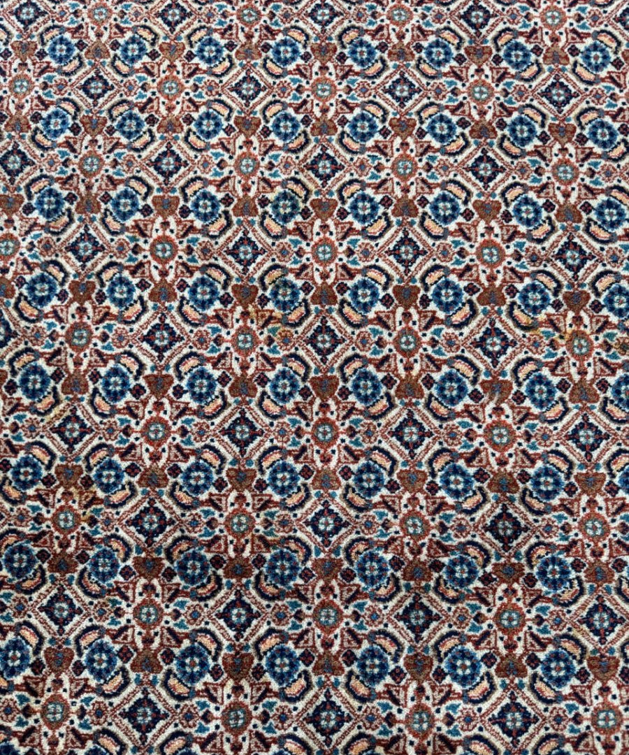 Close-up of Persian-style rug pattern in light blue, cream, and dark red