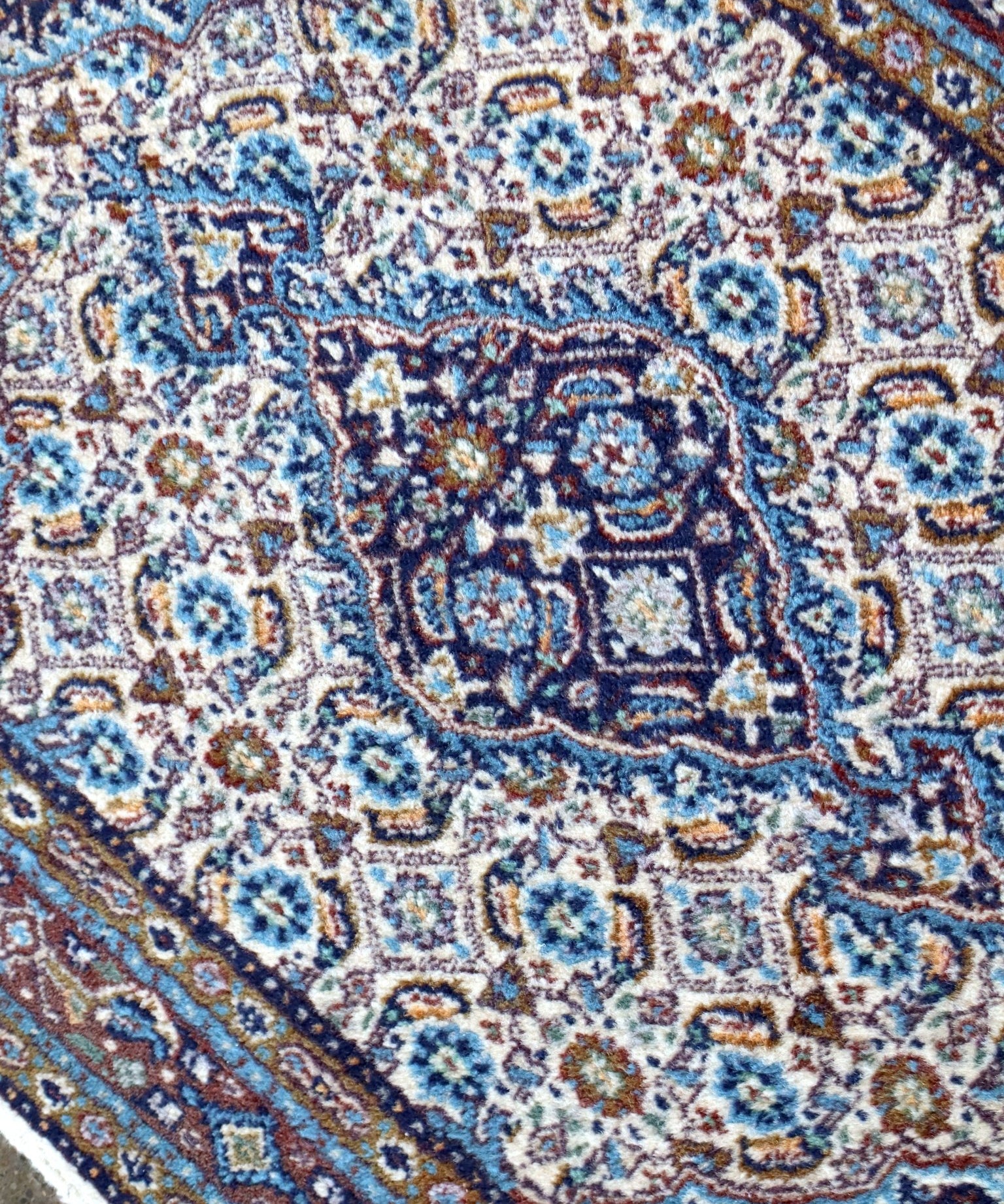 Close-up of Moud rug with blue, cream, and rust ornate central medallion details