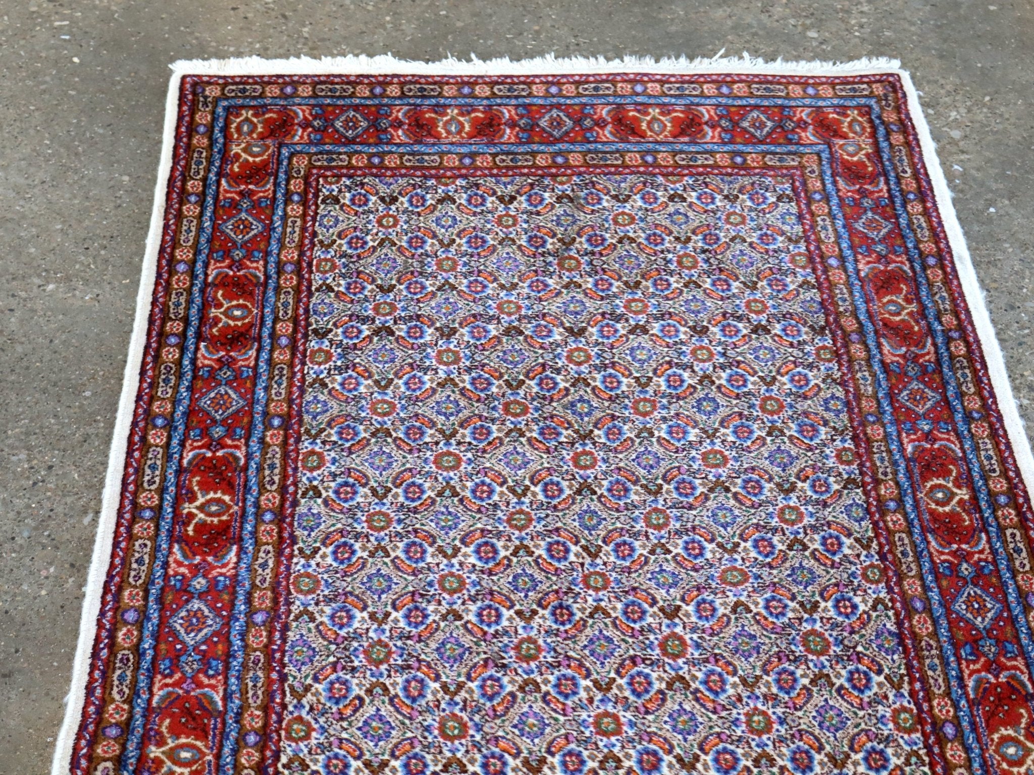 Top view of rug with central light field of blue floral motifs and red corner ornaments